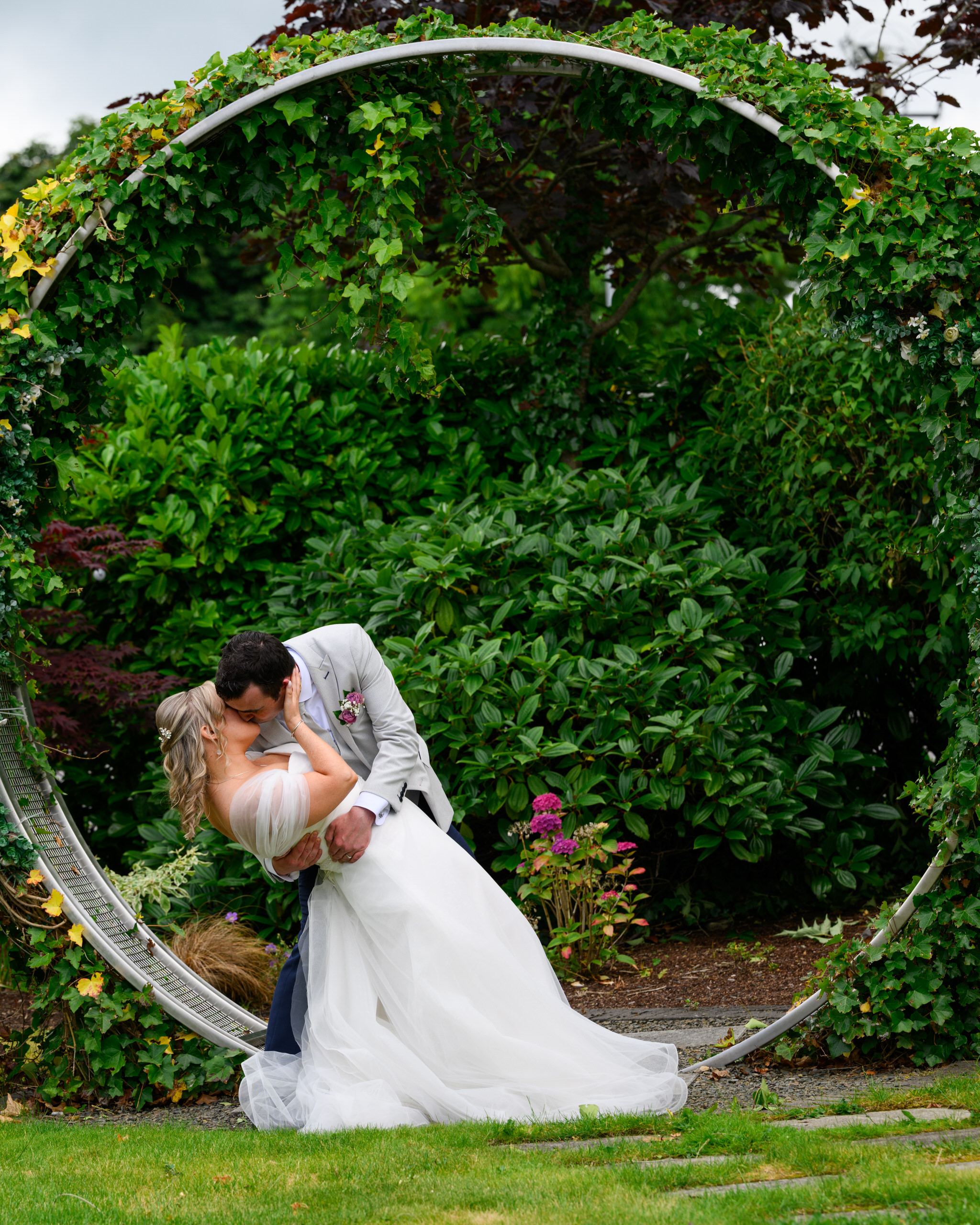 Bride and groom in romantic dip pose under floral arch in garden at Tullamore Court Hotel Offaly