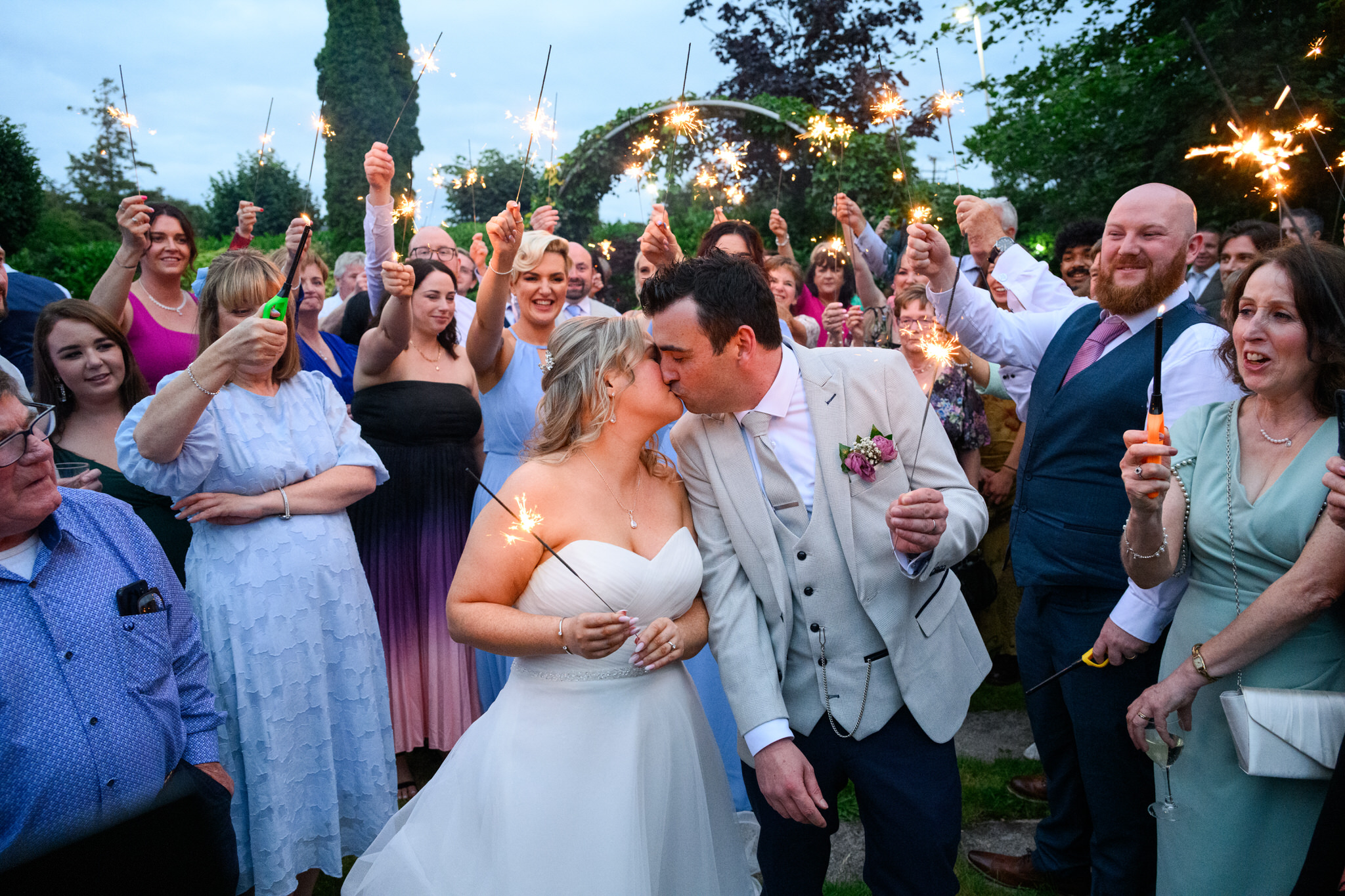 ride and groom kissing during sparkler celebration with guests at Tullamore Court Hotel wedding in Ireland