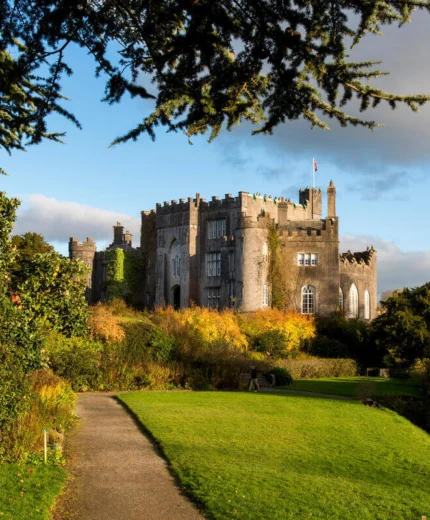A picturesque castle surrounded by lush greenery under a sunny sky.