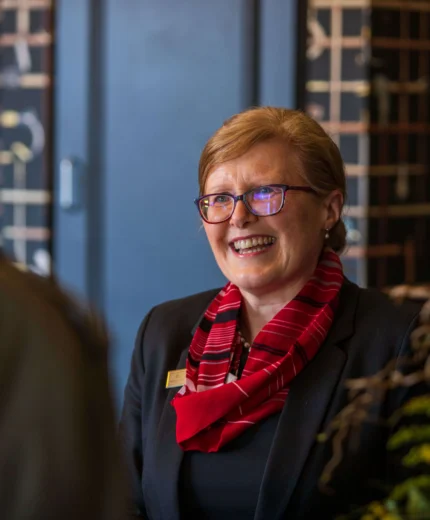Friendly hotel receptionist warmly greets guests with a smile in a welcoming lobby.