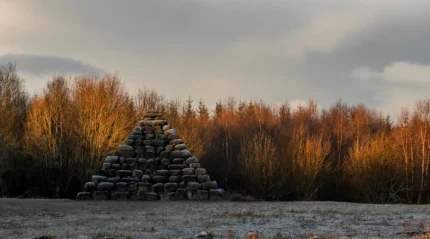 Stone pyramid by tranquil forest at sunset in countryside.