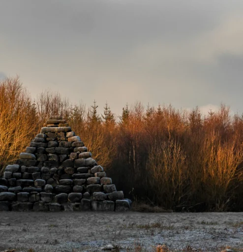 Stone pyramid by tranquil forest at sunset in countryside.