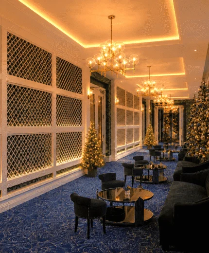 Elegant hotel lounge adorned with sparkling Christmas trees and cosy seating.