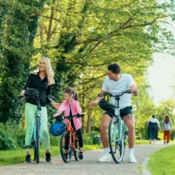Family cycling on a sunny path, lush greenery around.