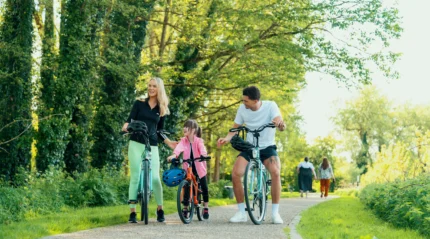 Family cycling on a sunny path, lush greenery around.