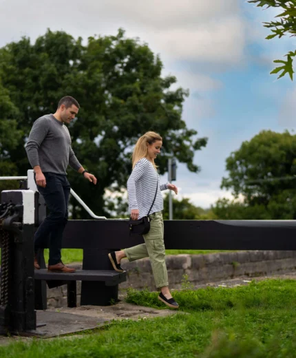 Couple enjoying a walk near a lock gate in a lush countryside setting.
