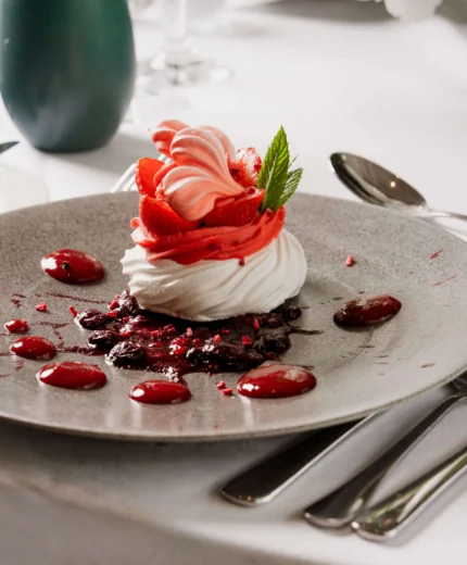 Elegant dessert with strawberries and cream on a table setting in a bright restaurant.