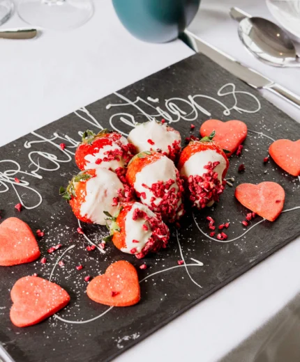 Elegant dessert with strawberries and heart-shaped treats on a decorated plate.