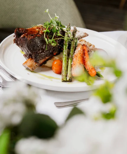 Elegant gourmet dish with roasted vegetables on a white tablecloth in a cosy restaurant.