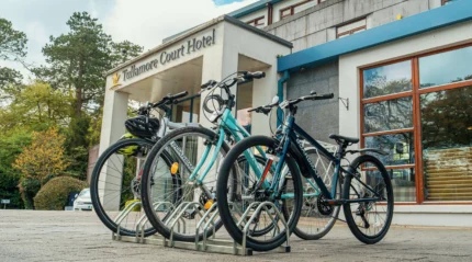 Four bicycles parked outside a hotel on a sunny day, ready for guests' adventures.