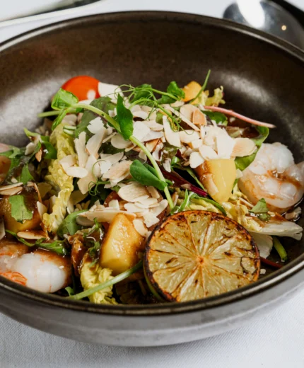 Fresh prawn salad with lime and almonds served on a white tablecloth.