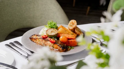 Elegant dining setup with grilled salmon and vegetables in a cosy hotel restaurant.