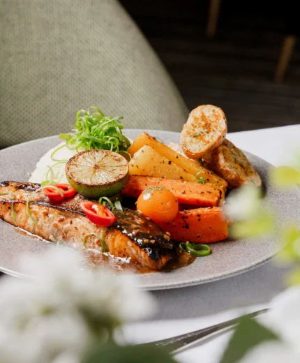 Elegant dining setup with grilled salmon and vegetables in a cosy hotel restaurant.