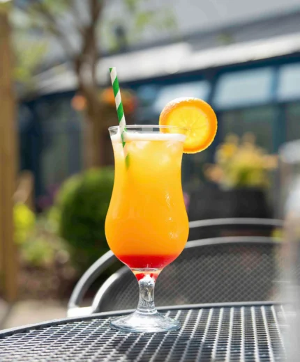 Refreshing cocktail on sunny hotel patio with lush greenery