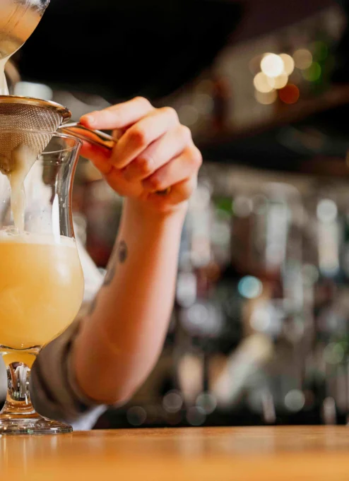 Bartender preparing a refreshing cocktail in a cosy bar setting.