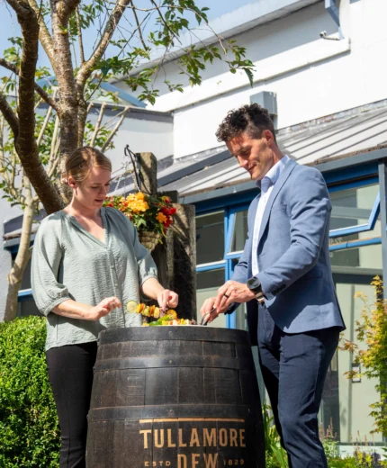Couple enjoying a sunny day by a whisky barrel at a resort.