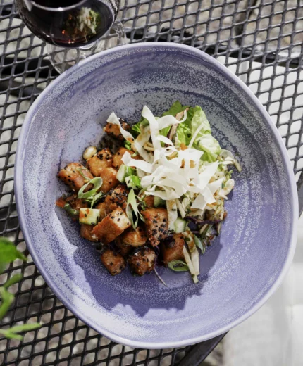 Outdoor dining with a vibrant dish and red wine at a hotel restaurant.