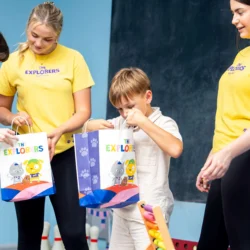 Smiling family opening gift bags at a hotel kids' club.