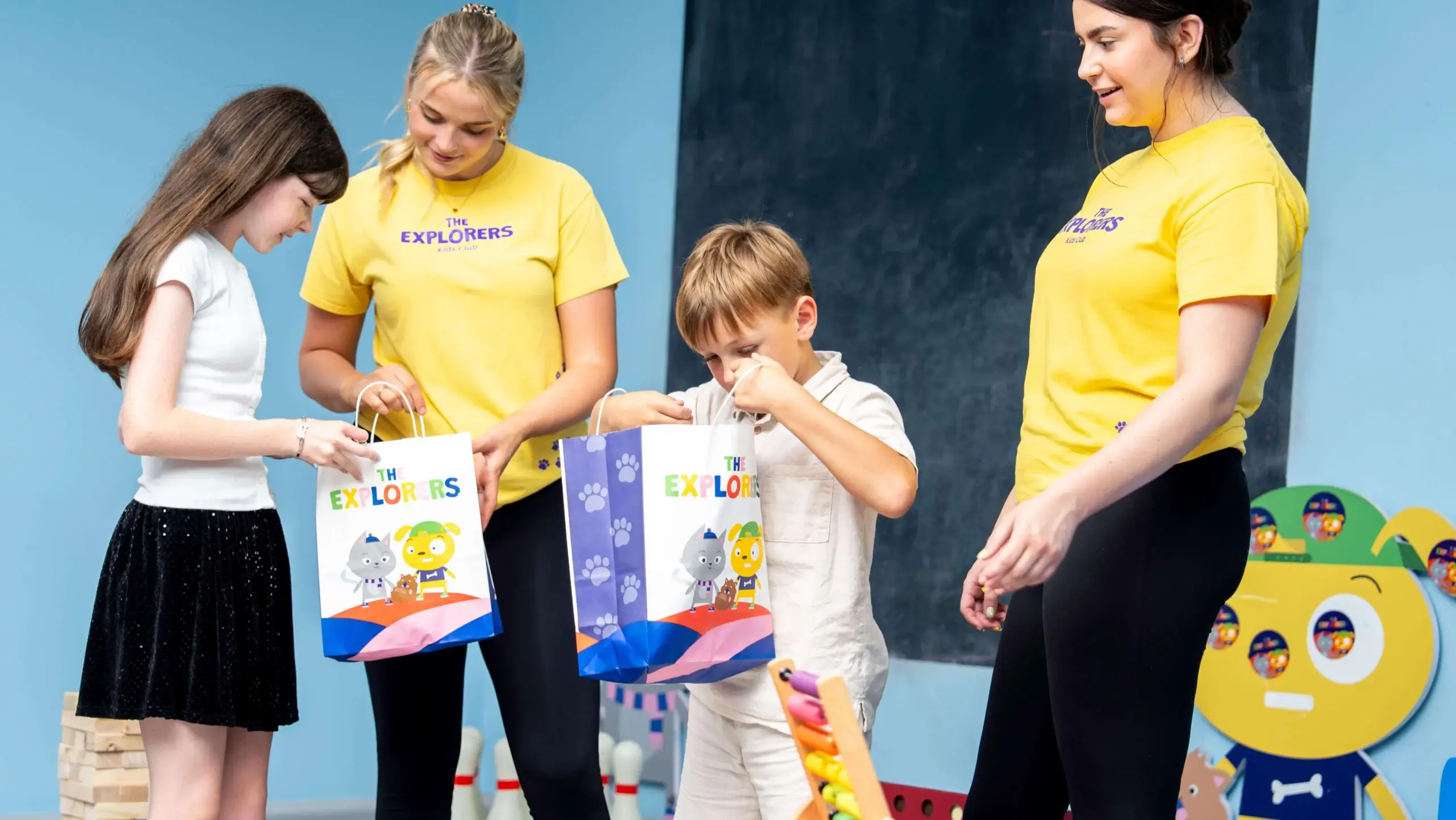 Smiling family opening gift bags at a hotel kids' club.