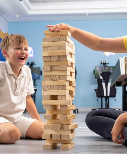 Child and carer playing Jenga at kids' club in vibrant, welcoming hotel setting.