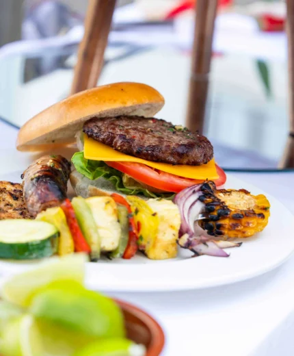 A delicious barbecue spread featuring burgers and grilled vegetables outdoors.