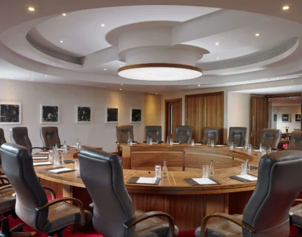 Elegant round conference room with leather chairs, set for a meeting at a luxury hotel.