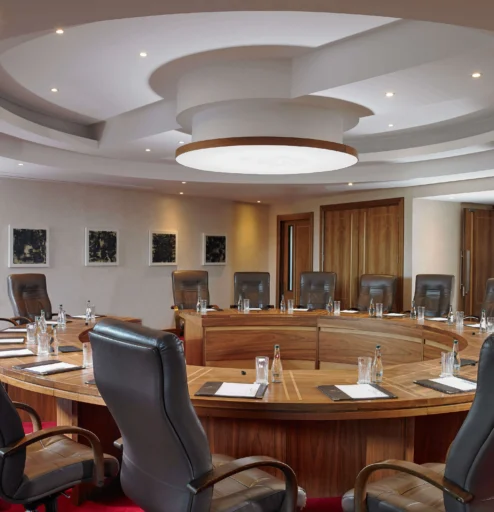 Elegant round conference room with leather chairs, set for a meeting at a luxury hotel.