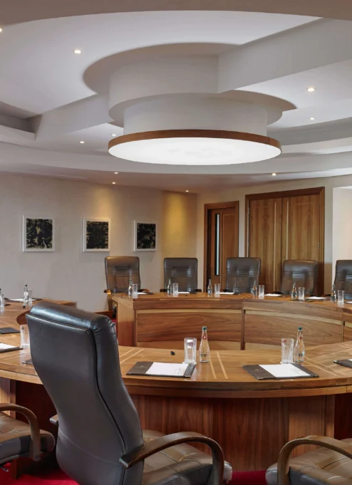 Elegant round conference room with leather chairs, set for a meeting at a luxury hotel.