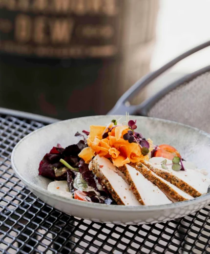 Elegant outdoor dining setting with a fresh salad and white wine on a sunny day.
