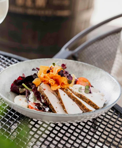Relaxing outdoor dining with gourmet meal and wine at a sunny resort terrace.
