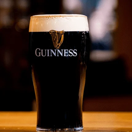 Pint of Guinness on a wooden bar in a cosy pub setting.