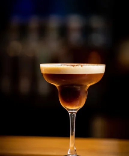 Elegant espresso martini on a wooden bar, evoking warm hospitality in a cosy atmosphere.