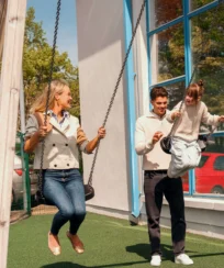 A cheerful family enjoys playing on swings at a sunny resort playground.
