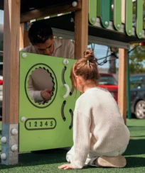 Parent and child playing at a sunny playground.