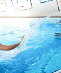 A father and daughter enjoy playtime in an indoor hotel pool with water features.