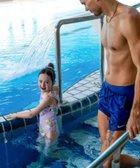 Family enjoying a leisurely swim in a hotel pool.