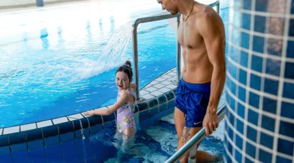 Family enjoying a leisurely swim in a hotel pool.