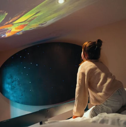 Family enjoying starry projection in cosy, inviting hotel room.