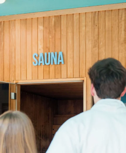 A couple in robes approaches a cosy sauna room at a hotel resort.