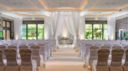 Elegant wedding venue with white decor, floral arrangements, and candles.
