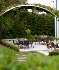 Charming outdoor dining area with tables set in lush garden at a hotel.