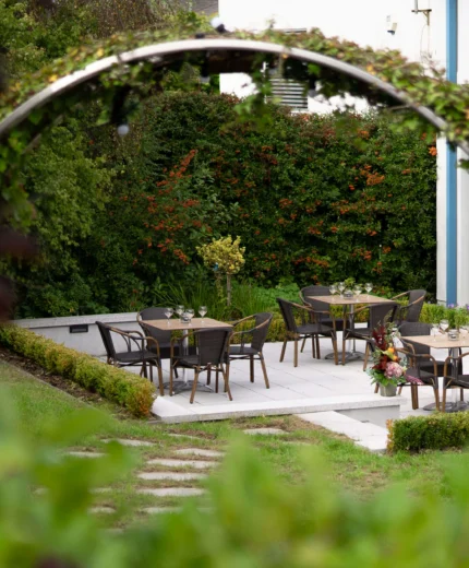 Charming outdoor dining area with tables set in lush garden at a hotel.