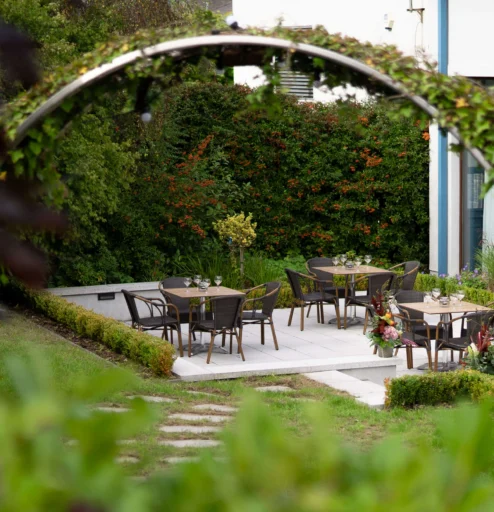 Charming outdoor dining area with tables set in lush garden at a hotel.
