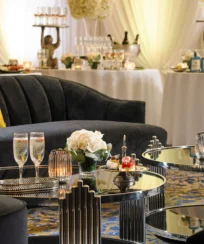 Elegant hotel lounge with champagne, floral decor, and plush seating.