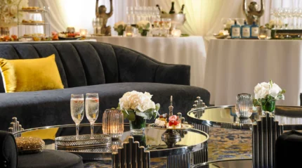 Elegant hotel lounge with champagne, floral decor, and plush seating.