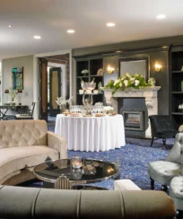 Elegant hotel lounge with plush seating, a round table with a floral centrepiece, and a welcoming ambiance.