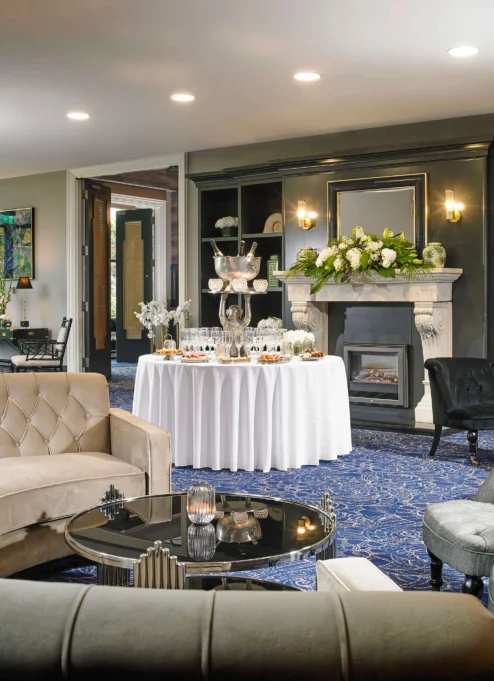 Elegant hotel lounge with plush seating, a round table with a floral centrepiece, and a welcoming ambiance.