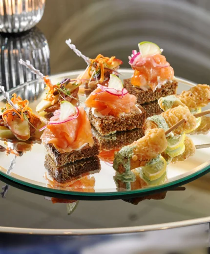 Elegant appetisers on a mirrored tray at a stylish hospitality event.