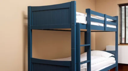 Cosy blue bunk bed in a welcoming hotel room with natural light from the window.