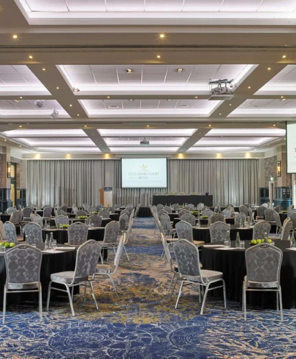 Elegant banquet hall set for a hospitality event with round tables and silver chairs.